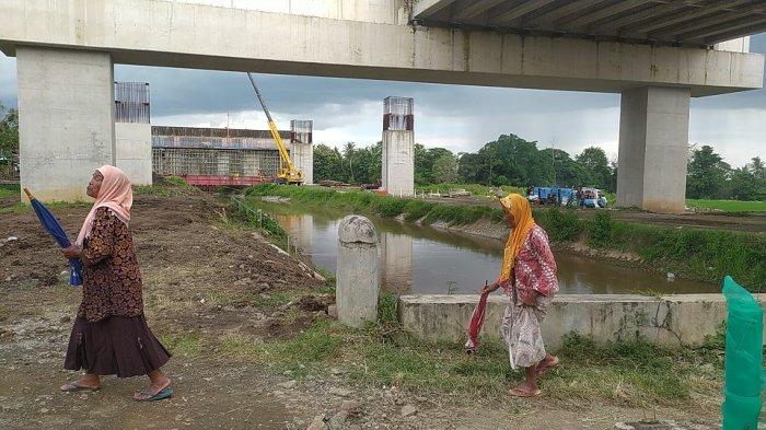 TOL YOGYAKARTA BAWEN SEKSI 1: Warga melintas di bawah jalur pembangunan Tol Yogyakarta-Bawen seksi 1 di atas selokan Mataram yang menghubungkan junction Sleman hingga Simpang Susun Banyurejo, Rabu (26/2/2025)
