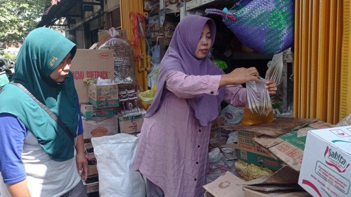 Era, pedagang di Pasar Wates sedang melayani pembeli minyak goreng curah, Kamis (30/6/2022).