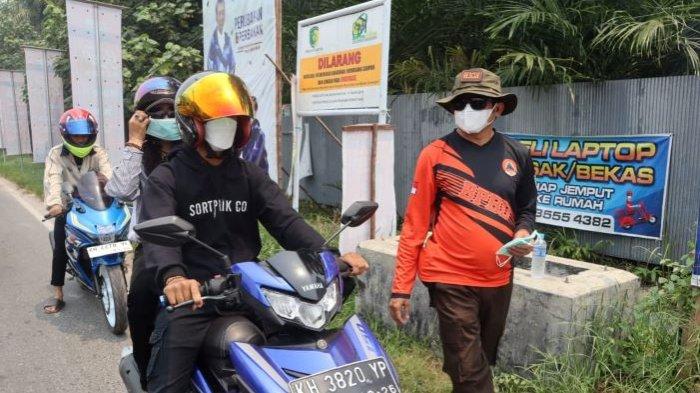 Petugas Satgas Karhutla di Palangkaraya saat membagikan masker untuk pengendara. Dampak Karhutla di Palangkaraya juga asap kiriman dari kabupaten tetangga membuat Indeks standar pencemaran udara (ISPU) di Palangkaraya berstatus Sangat Tidak Sehat.