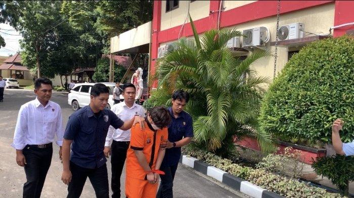 DIGIRING POLISI - Tersangka AJ saat digiring petugas kepolisian untuk hadiri press rilis di Mapolda Kalteng, Jumat (16/5/2025).