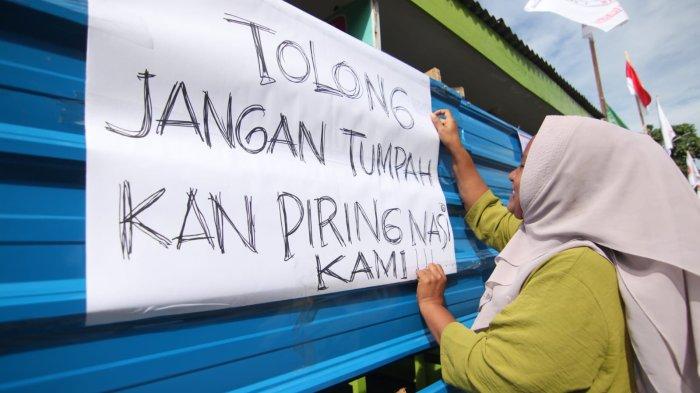 Seorang pedagang terdampak pemagaran Pasar Klandasan, Nana (34) menempelkan selebaran yang memohon pihak-pihak yang bersengketa agar memperhatikan nasib para PKL. Dia menulis