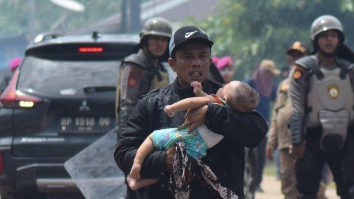 Seorang warga Pulau Rempang, Kecamatan Galang, Kota Batam, Provinsi Kepulauan Riau (Kepri) menyelamatkan seorang bocah yang terkena gas air mata saat terjadi bentrokan dengan polisi dan TNI, Kamis (7/9/2023).