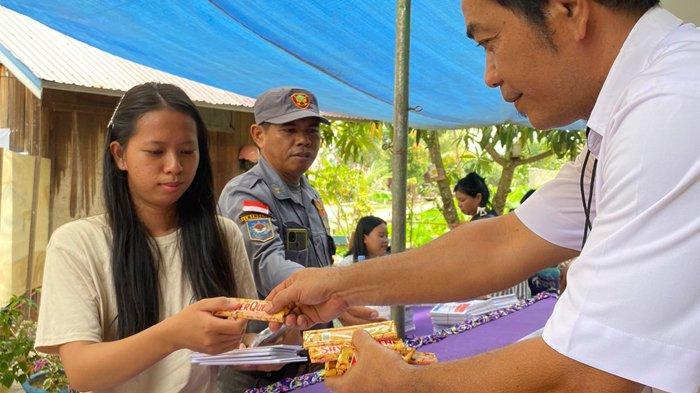 COKELAT USAI COBLOS - Ketua RT 18 Mathius John Tangdillalo menyerahkan cokelat Silverqueen kepada pemilih Pemilu 2024 di TPS 32 Desa Singa Gembara, Kecamatan Sangatta Utara, Kabupaten Kutai Timur, Kalimantan Timur, Rabu (14/2/2024).