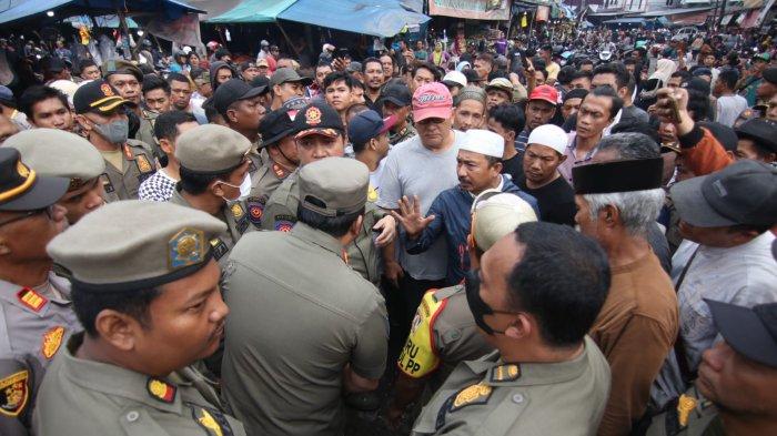 PENERTIBAN PASAR PANDANSARI - Aziz (jaket biru), seorang pedagang sayur di Pasar Pandansari, Balikpapan, berdiri tegar di depan lapaknya yang hendak ditertibkan petugas Satpol PP. Ia menolak penggusuran dan menuntut solusi relokasi yang layak bagi para pedagang.