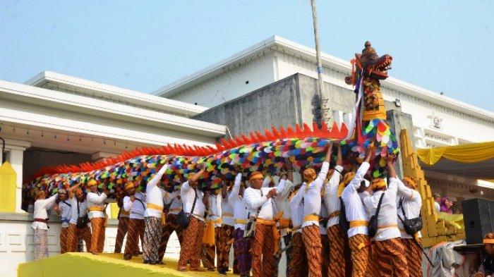 Belasan orang menggotong replika naga dari dalam Keraton Kesultanan Kutai. Sepasang replika naga ini dibawa ke kapal yang bersandar di dermaga depan Keraton. Naga ini akan dibawa ke Kutai Lama, Kecamatan Anggana untuk dilarungkan ke Sungai Mahakam.