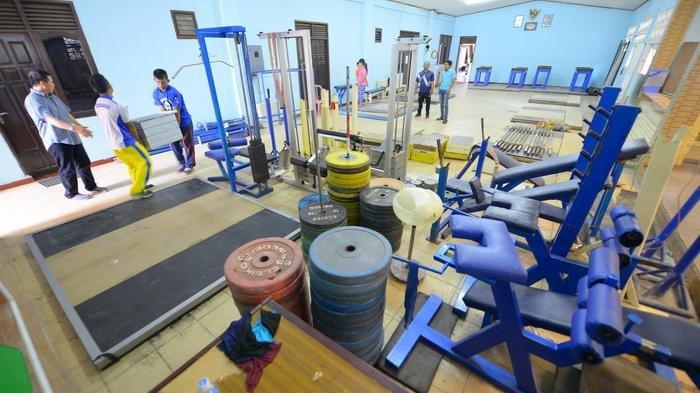 Ilustrasi-Para atlet mengumpulkan perkakas latihan angkat besi seperti stick barbell dan disc barbell yang disusun rapi di depan pintu masuk GOR Hevindo, Balikpapan