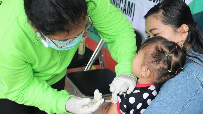 Penyuntikan vaksin difteri di pos pelayanan kesehatan .