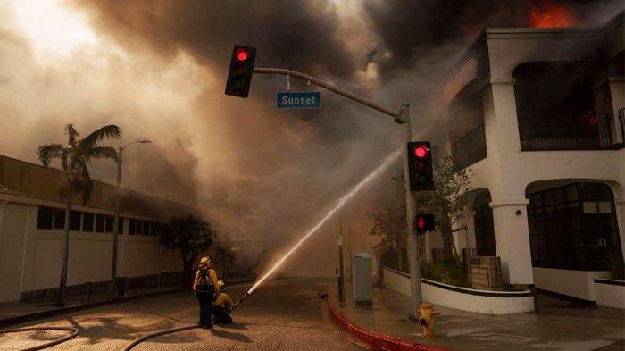 Petugas pemadam kebakaran menyemprotkan api di kawasan Pacific Palisades, Los Angeles, California, (Rabu (8/1/2025). Sejumlah kebakaran hutan yang dipicu oleh Angin Santa Ana yang kencang membakar wilayah Los Angeles County.