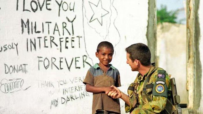Seorang tentara INTERFET Australia berbicara dengan seorang anak laki-laki di Timor Timur.