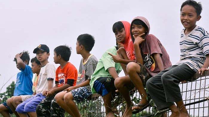 Warga yang tidak memiliki tiket menonton dari luar pagar pembatas Sirkuit Selaparang dekat permukiman warga, Sabtu (1/7/2023).