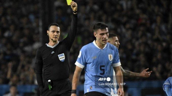Wasit Kolombia Wilmar Roldan memberikan kartu kuning kepada gelandang Uruguay Manuel Ugarte selama pertandingan sepak bola kualifikasi Amerika Selatan Piala Dunia FIFA 2026 antara Argentina dan Uruguay di stadion La Bombonera di Buenos Aires pada 16 November 2023.