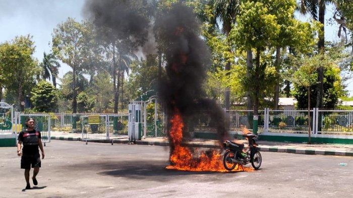 Zaini Werwer, menyaksikan sepeda motor Honda Supra miliknya, yang baru saja dibakar, di area monumen Arek Lancor, Pamekasan, Kamis (19/10/2023).