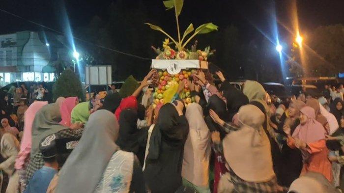 Warga berebut gunungan buah-buahan di momen Cocogen, peringatan kehadiran Bulan Rabi’ul Awal, bulan kelahiran Baginda Nabi Muhammad SAW yang digelar di Komplek Pesarean Syaikhona Kholil, Desa Martajasah, Kota Bangkalan, Rabu (4/9/2024) malam