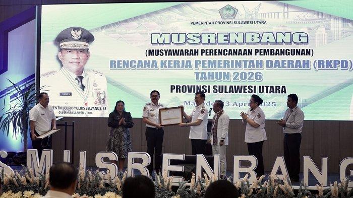 PENGHARGAAN - Wakil Gubernur Sulawesi Utara, Bapak Dr. J. Victor Mailangkay menyerahkan sertifikat penghargaan dari BPS kepada Bupati Minut Joune Ganda dan Hukum Tua Desa Watudambo II Ida Rotty, atas capain prestasi Desa Cantik di momen Musrenbang RKPD Provinsi Sulut 2026.