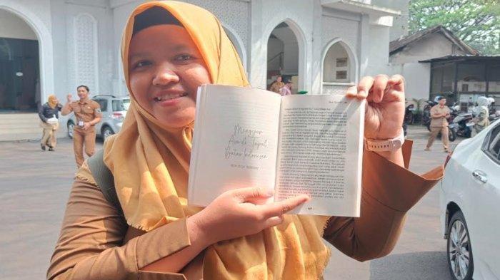 PENGALAMAN GURU DI PERBATASAN - Heni Yulia Wardhani, guru Bahasa Indonesia dan Bahasa Daerah di SMPN 25 Kota Malang, saat menunjukkan tulisannya dalam buku antologi yang ia tulis bersama sejumlah guru SMP di Kota Malang pada Selasa (24/6/2025)