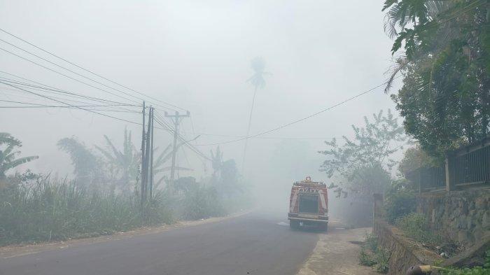 Jalan yang tertutup asap karena kebakaran di TPA Sumompo Manado