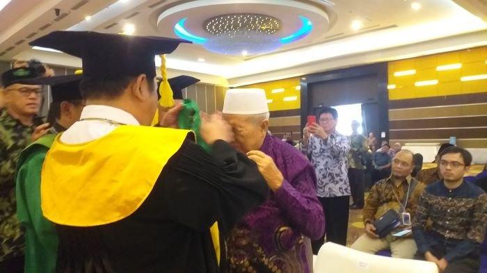 Direktur Jenderal Pendidikan Islam Kementerian Agama RI, Muhammad Ali Ramdhani, saat memberikan kalung pengukuhan guru besar kepada ayah Rektor IAIN Manado, Prof Dr Ahmad Rajafi MHI.