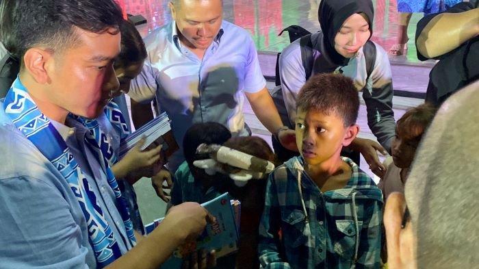 BAGI BUKU - Potret Gibran Bagi-Bagi Buku saat Perayaan Natal di Amphitheather Minut Sulawesi Utara pada Sabtu (23/12/2023)