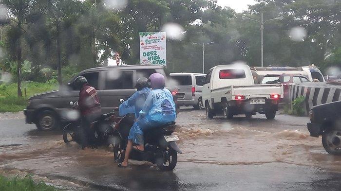 Kendaraan saat melewati jalan berlubang dengan derasnya air yang meluap. Terlihat seorang bapak hampir terjatuh akibat jalan lubang,