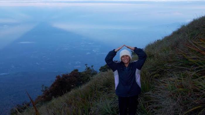 Pendaki berpose di depan fenomena alam langka 'Shadow Triangle', yaitu bayangan segitia Gunung Klabat saat matahari terbit, dan langit tak berkabut. Foto diambil dari atas puncak Gunung Klabat, puncak tertinggi Sulawesi Utara, di ketinggain 1.995 MDPL. (TRIBUNMANADO/FRANSISKA NOEL)