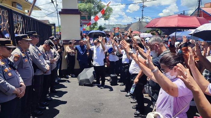BERDOA - Para pendeta dan Jemaat GMIM memberi support kepada Ketua Sinode GMIM Pendeta Hein Arina di depan Mapolda Sulut, Kamis (17/4/2025). Mereka tampak bernyanyi