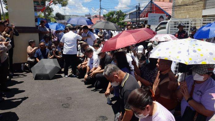 BERDOA - Sejumlah umat Gereja Masehi Injili di Minahasa (GMIM) melakukan aksi berdoa di depan Mapolda Sulut, Kamis (17/4/2025) siang. Mereka berdoa supata Hein Arina diberi kekuatan. (Arthur Rompis/Tribun Manado)