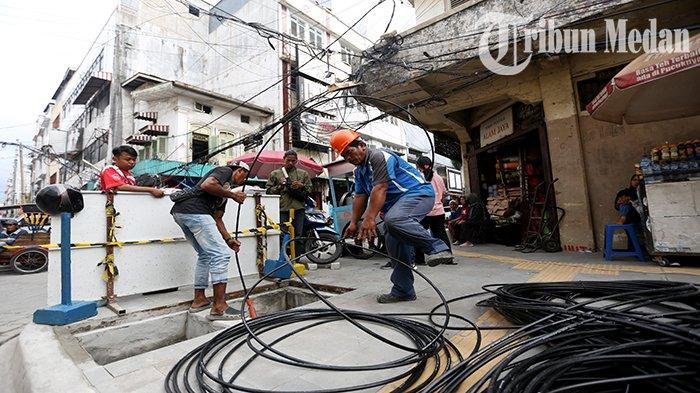 Sejumlah petugas menarik jaringan kabel utilitas yang tertanam di Jalan Perniagaan, Kota Medan, Senin (7/8). Pemko Medan melakukan penataan kabel utilitas di delapan belas ruas jalan Kota Medan sebagai upaya menghadirkan kenyamanan serta keselamatan warga dan ditargetkan selesai pada akhir tahun 2023.