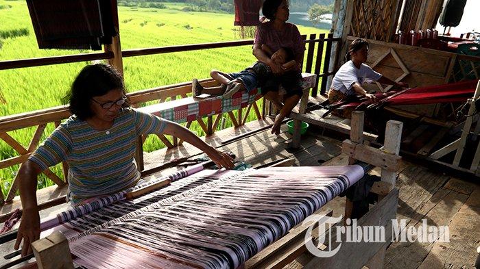 Perajin menyelesaikan kain tenun ulos Khas Batak di Desa Meat, Kecamatan Tampahan, Kabupaten Toba, Sumatera Utara, Kamis (9/6/2022). Desa Meat memiliki pesona alam yang indah, letak persawahan tepat di pinggir Danau Toba dan warga memiliki keahlian membuat kerajinan kain ulos khas Batak.