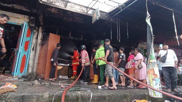 Personel pemadam kebakaran Kabupaten Karo dibantu warga melakukan pemadaman dan pendinginan kios emas yang terbakar di kawasan Pusat Pasar Kabanjahe, di Jalan Kapten Bangsi Sembiring, Kabanjahe, Minggu (25/2/2024).