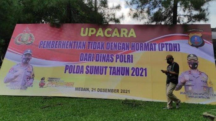 Seorang pria melintas di baliho pemberhentian tidak dengan hormat (PTDH) dari dinas Polri Polda Sumut, Selasa (21/12/2021).