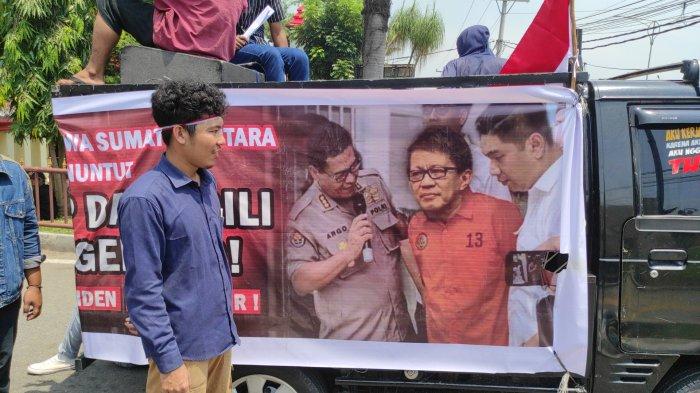 Spanduk yang dibawa mahasiswa mendesak polisi penjarakan Rocky Gerung, di Polda Sumut, Jumat (4/8/2023). Mereka membawa spanduk Rocky mengenakan baju tahanan berwarna merah.