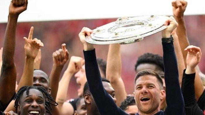 Pelatih Bayer Leverkusen, Xabi Alonso, mengangkat gelar trofi juara Bundesliga setelah timnya menang 2-1 atas FC Augsburg di BayArena, Sabtu (18/5/2024). (STUART FRANKLIN/AFP)