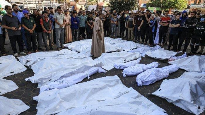 Seorang pria berjalan di antara mayat-mayat yang terbungkus kafan dari mereka yang tewas dalam pemboman Israel di Deir Balah di Jalur Gaza tengah, di rumah sakit Shuhada Al-Aqsa di kota yang sama pada 6 November 2023, di tengah pertempuran yang sedang berlangsung antara Israel dan kelompok Palestina Hamas.