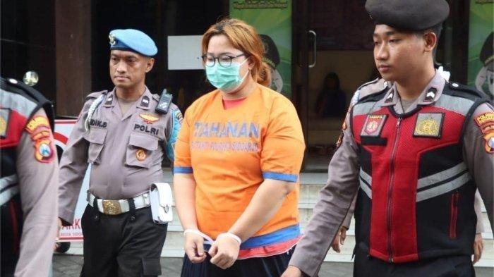 IBU ANIAYA ANAK - Tersangka ibu yang telah menganiaya anaknya dengan memukuli dan menyiram menggunakan air panas saat digelandang di Polresta Sidoaro, Sabtu (15/2/2025). Ibu asal Candi, Sidoarjo ini tega menyiram anaknya menggunakan air panas hanya karena sang anak ngompol di kasur.