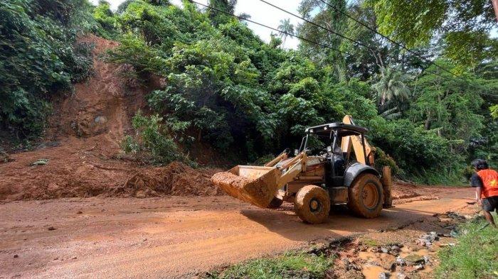 Alat berat tengah membersihkan jalan dari material longsor yang terjadi di dekat Lantamal II Padang, Minggu (13/10/2024) jelang sore.