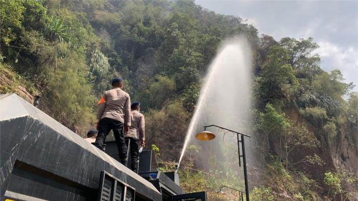 KARHUTLA DI SUMBAR- Petugas kepolisian saat membantu memadamkan api yang membakar lahan perbukitan dengan menggunakan kendaraan water cannon di Jorong Lubuak Limpato, Nagari Tarantang, Kecamatan Harau, Kabupaten Lima Puluh Kota, Sumatera Barat, Rabu (23/7/2025). Lokasi Karhutla berjarak 16 kilometer dari Kota Payakumbuh.
