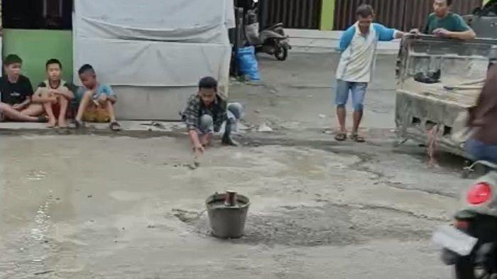 TAMBAL JALAN BERLUBANG - Tangkapan layar viral warga perbaiki jalan berlubang di kawasan Pasar Alai, Kelurahan Alai Parak Kopi, Kecamatan Padang Utara, Kota Padang. Jalan ini sempat menyebabkan seorang pengendara beserta anaknya terjatuh dan mengalami luka.