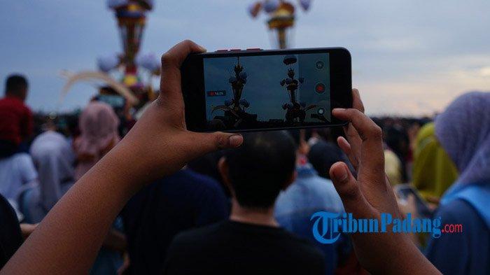 Warga merekam momen prosesi mambuang Tabuik ke laut dengan telepon mereka di Pantai Gondoriah Kota Pariaman Sumatera Barat, Minggu (14/8/2022).