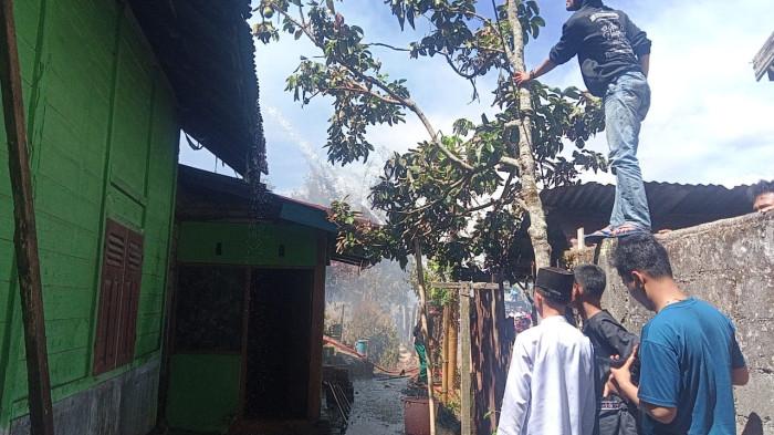 KEBAKARAN RUMAH- Warga saat melihat proses pemadaman api oleh petugas pemadam kebakaran di Jalan Raya Pasia, Pasia, Kabupaten Agam, Sumatera Barat, Jumat (18/7/2025).