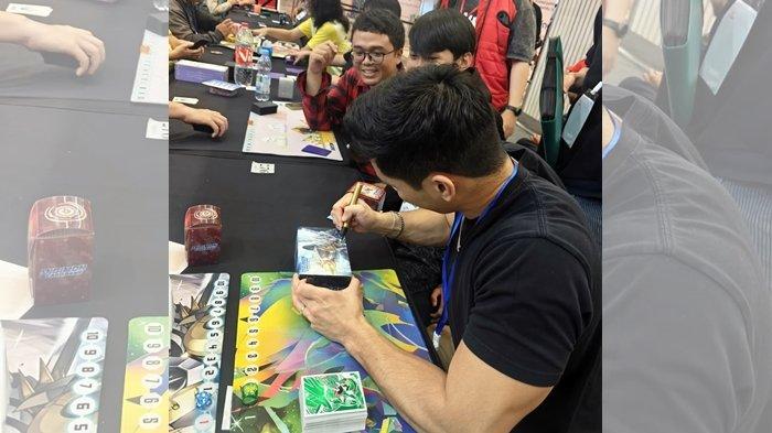 Yoshi Sudarso menandatangani merch Digimon penggemar pada saat pertandingan Digimon Card Game di event Bandai Card Games Festival 24-25 World Tour di Jakarta.