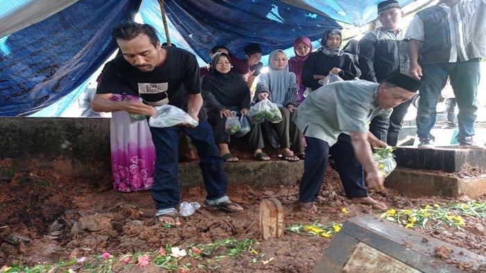 Kurniawan (kiri) menaburkan bunga ke pusara makam istri dan anaknya, Wasilah dan Faras yang di pemakaman TPU Puncak Sekuning, Selasa (16/4/2024). Kedua jenazah ini adalah korban pembunuhan yang terjadi di Jl Karya Baru, Macan Lindungan, Kecamatan Ilir Barat I Palembang. SYAHRULHIDAYAT