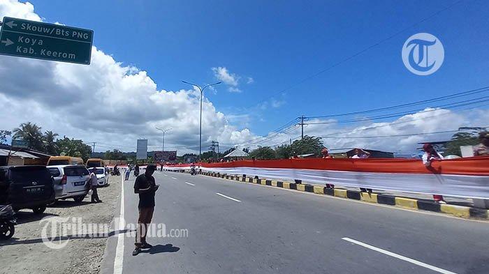Bendera Merah Putih sepanjang 11 kilometer dibentangkan mulai jalan ringroad Hamadi sampai PLTU Holtekamp, Kota Jayapura, Papua, Rabu (1/5/2024). Pembentangan kain merah putih digelar dalam rangka memperingati Hari Integrasi Papua ke dalam bingkai Negara Kesatuan Republik Indonesia (NKRI) pada 1 Mei 1961.