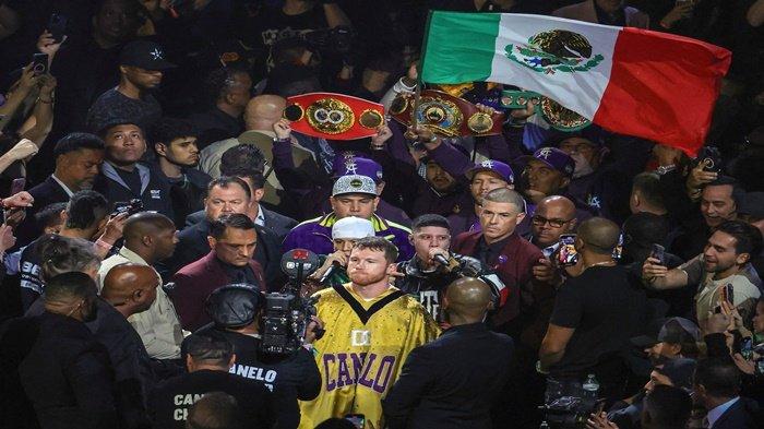 Canelo Alvarez (tengah), diapit oleh rapper Tornillo Vazquez (Kiri) dan Santa Fe Klan (kanan), melakukan ring walk untuk perebutan gelar kelas menengah super melawan Jermell Charlo di T-Mobile Arena pada bulan September 30 Agustus 2023 di Las Vegas, Nevada. Alvarez menang dengan keputusan bulat.