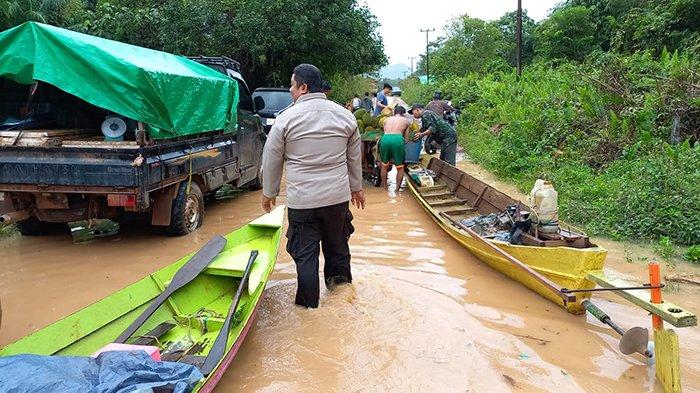 Personel dari Polsek Jelai Hulu saat membantu warga melintas menggunakan perahu.