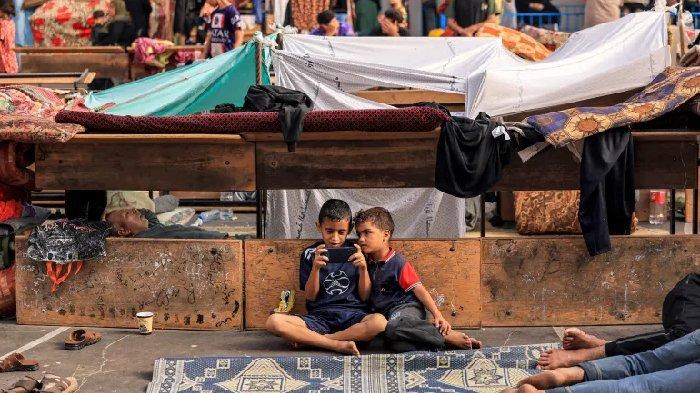 Anak-anak duduk bersama di sekolah milik PBB yang telah diubah menjadi tempat penampungan bagi pengungsi Palestina di Khan Younis di Jalur Gaza selatan pada 25 Oktober