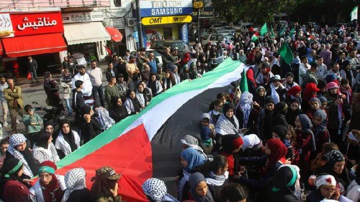 Demonstran membawa bendera Palestina yang besar selama protes di kota Sidon di selatan Lebanon pada Minggu (10/12/2023).