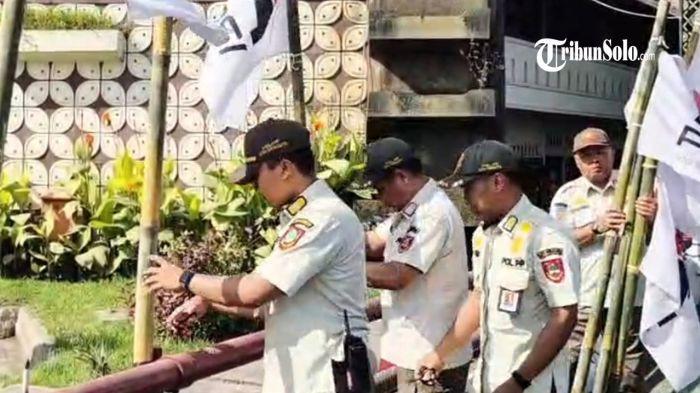 DICOPOT - Menjelang kongres, Bendera Partai Solidaritas Indonesia (PSI) dengan logo barunya dicabut oleh Satpol PP Kota Surakarta lantaran dipasang di white area, Rabu (16/7/2025). Di area ini reklame dalam bentuk apa pun dilarang.