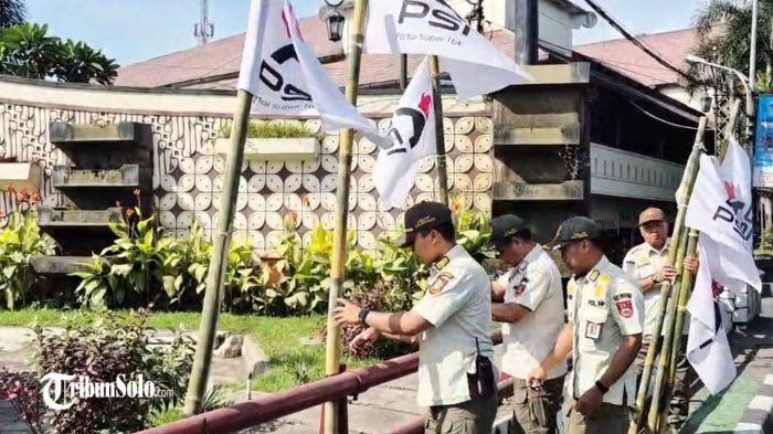 DICOPOT - Menjelang kongres, Bendera Partai Solidaritas Indonesia (PSI) dengan logo barunya dicabut oleh Satpol PP Kota Surakarta lantaran dipasang di white area, Rabu (16/7/2025). Di area ini reklame dalam bentuk apa pun dilarang.