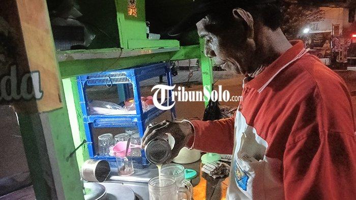 Ranto (60) tengah menghidangkan minuman tradisional yang dibuatnya dengan meracik 15 macam rempah-rempah