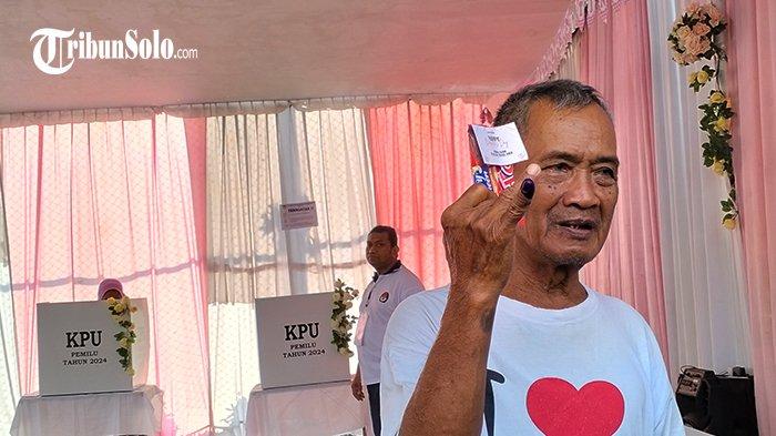 Warga yang selesai menggunakan hak suaranya menunjukkan jari yang telah tercelup tinta dan coklat yang didapat dari petugas KPPS TPS 34, Kelurahan Manahan, Kecamatan Banjarsari, Kota Solo, Rabu (14/2/2024).